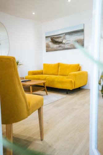 a living room with a yellow couch and a table at The Old Captains Lookout in Falmouth