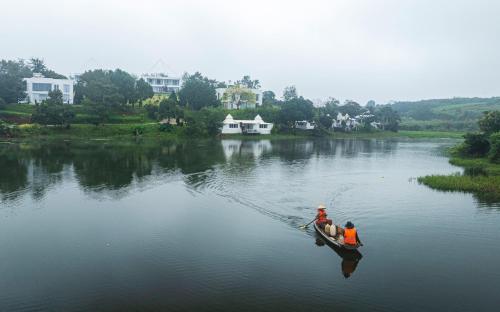 two people are in a boat on a river at Du Lịch Lâm Hà - Hồ Gia Trang Villas in Lam Ha