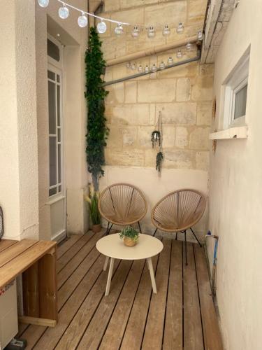 a patio with two chairs and a table on a wooden floor at Auma Home in Bordeaux