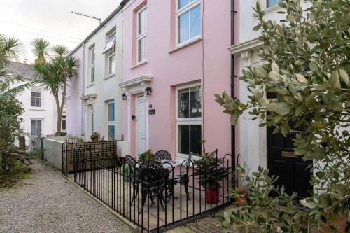 a row of pink and white houses with a table at Peaceful & Tranquil Cottage With Private Terrace at 'The Pink House' in Falmouth