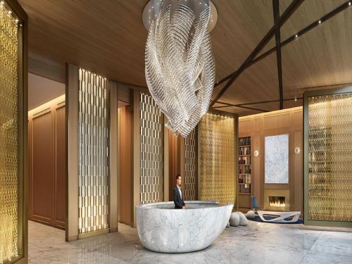 a person standing in a lobby with a large chandelier at Global Luxury Suites at Sky in New York