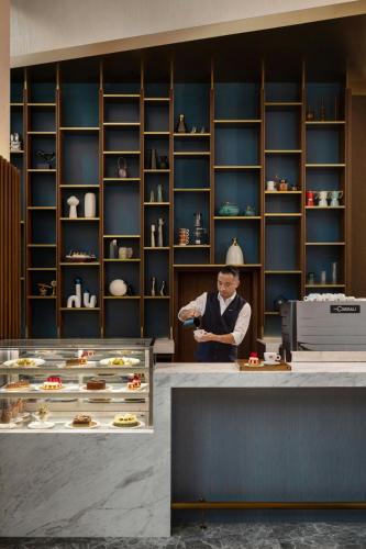 a man standing behind a counter with a plate of food at Le Méridien Hong Kong, Cyberport in Hong Kong