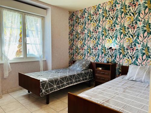 a bedroom with two beds and a wall with a floral wallpaper at Maison située dans longère 6 à 8 personnes proche du bourg de Guidel - ALARIC in Guidel