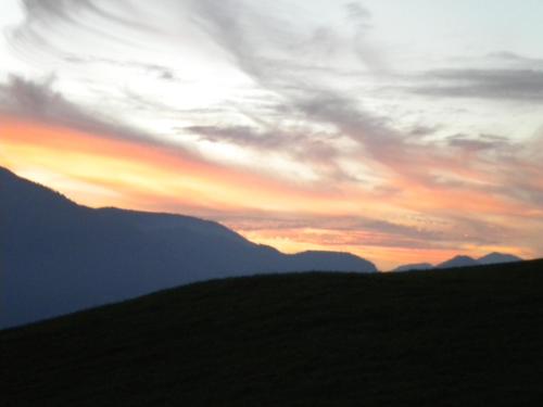 a sunset over a field with mountains in the background at Auerhiasbauer in St. Wolfgang