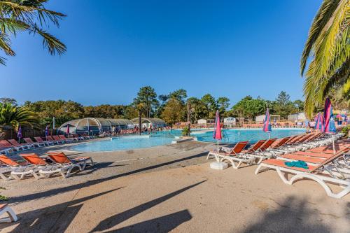 une piscine avec des chaises longues et une plage dans l'établissement La Ressource des Dunes, à Lège-Cap-Ferret