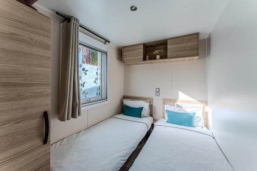 deux lits dans une petite pièce avec une fenêtre dans l'établissement La Ressource des Dunes, à Lège-Cap-Ferret