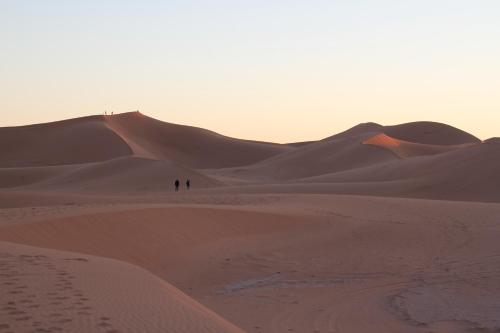 two people walking on the sand in the desert at Erg Chigaga Wil Camp in El Gouera