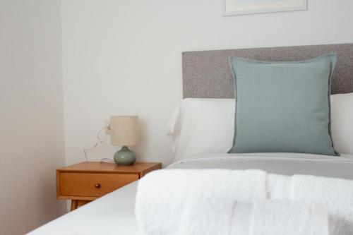 a bedroom with a bed with a blue pillow and a nightstand at A Paradiña de Sarria in Sarria