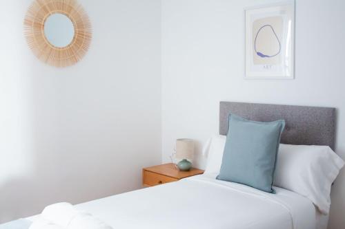 a white bed with a blue pillow and a mirror at A Paradiña de Sarria in Sarria
