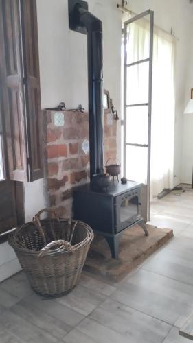 a wood stove in a room with a basket at Casa De Campo El Corral in Carmen de Areco