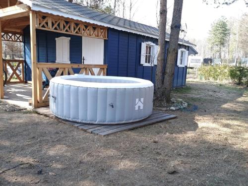 a hot tub sitting outside of a blue house at Domki na Kociewiu Mia in Bożepole Królewskie