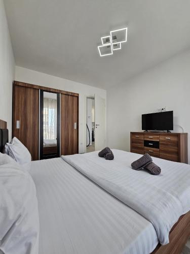 a bedroom with a large white bed with two towels on it at Coresi Mall Luxury Apartment in Braşov