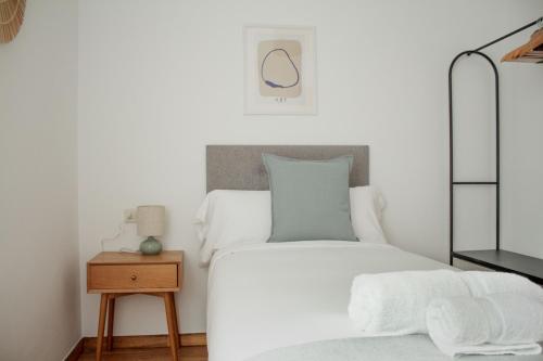a white bedroom with a bed and a night stand at A Paradiña de Sarria in Sarria