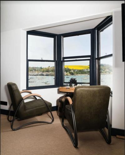 a room with a chair and a table and windows at Stunning Waterfront Apartment With Spectacular Views & Parking at 'CAPTAINS LOFT' in Falmouth