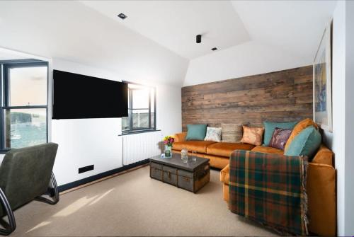 a living room with a couch and a flat screen tv at Stunning Waterfront Apartment With Spectacular Views & Parking at 'CAPTAINS LOFT' in Falmouth