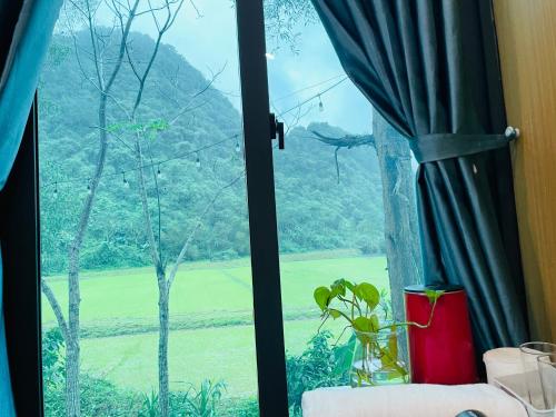 a window with a view of a green field at Hieu-Homestay in Phong Nha