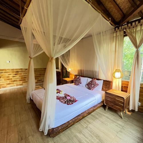 a bedroom with a bed with mosquito nets at Yoga Maya Villa in Gianyar