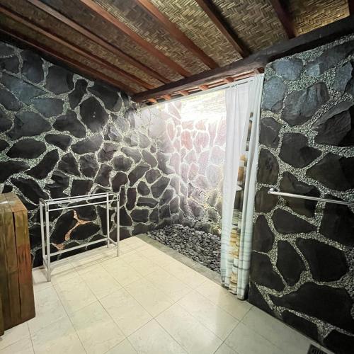 a stone wall in a bathroom with a shower at Yoga Maya Villa in Gianyar