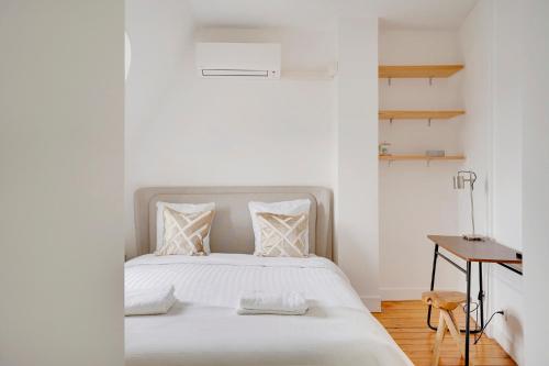 - une chambre avec un lit avec des draps blancs et une table dans l'établissement Loft d'exception Courcelles - parc Monceau, à Paris