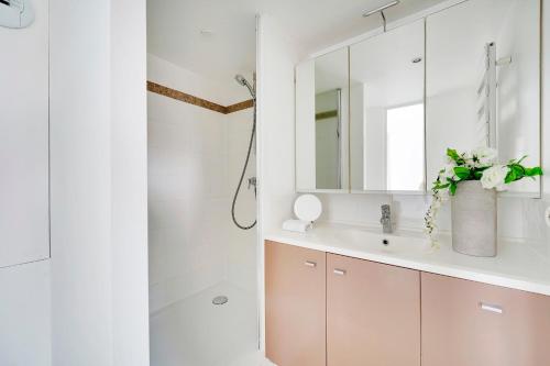 une salle de bain blanche avec un lavabo et un miroir dans l'établissement Loft d'exception Courcelles - parc Monceau, à Paris