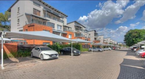 a parking lot with cars parked in front of a building at Easy Stay 2 Bedroom Apartment Oakdene Near Glen Mall in Johannesburg