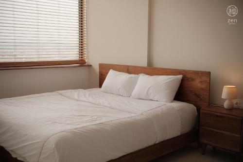 une chambre avec un lit avec des draps blancs et une fenêtre dans l'établissement Zen Apartment - Nera Garden Hue, à Thôn Văn Dương