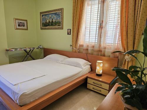 ヴロラにあるGEARD Apartamentのベッドルーム1室(ベッド1台、植物、窓付)