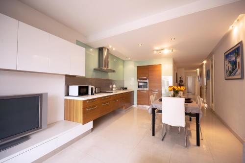 a kitchen and dining room with a table and a television at Large & modern 3 bedrooms near Spinola Bay MMAI1-3 in St. Julianʼs