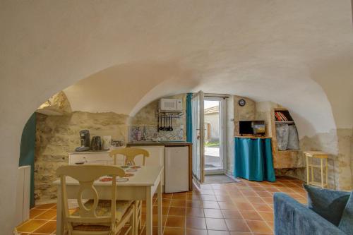 une cuisine avec une table et des chaises dans une pièce dans l'établissement Le Studio, Saint-Restitut, à Saint-Restitut
