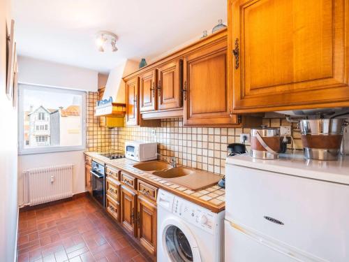 une cuisine avec des armoires en bois et une laveuse et une sécheuse dans l'établissement Appartement au cœur du Touquet avec balcon, parking et wifi - FR-1-821-23, à Le Touquet-Paris-Plage