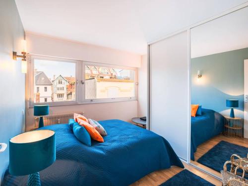 une chambre avec un lit bleu et une grande fenêtre dans l'établissement Appartement au cœur du Touquet avec balcon, parking et wifi - FR-1-821-23, à Le Touquet-Paris-Plage