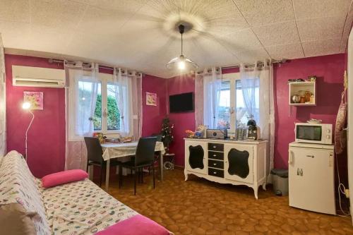 a bedroom with pink walls and a dining room with a table at Appartement charmant à Saint-Victor-de-Cessieu - 30 m² - Terrasse in Saint-Victor-de-Cessieu