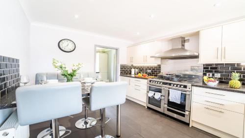 a kitchen with white cabinets and a stove top oven at Burgess Beach House in Caister-on-Sea