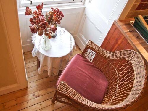 a wicker chair and a table with a vase of flowers at Bank View in Duns