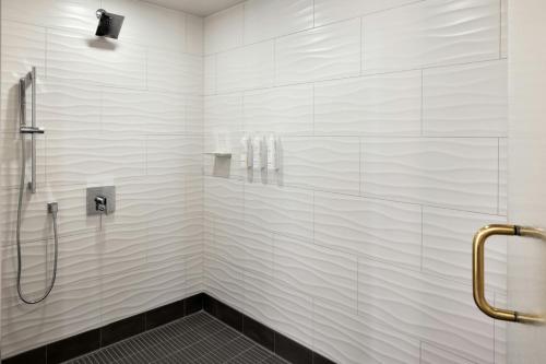 a bathroom with a shower with white tiles at Marriott Bloomington Normal Hotel and Conference Center in Bloomington