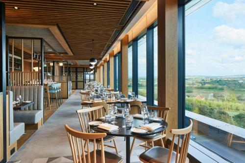a restaurant with tables and chairs and large windows at Courtyard by Marriott Exeter Sandy Park in Exeter
