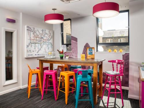 a dining room with colorful stools around a wooden table at Astor Oxford Street in London