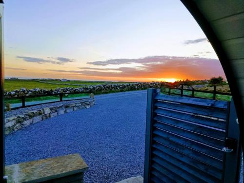 a sunset over a gate with a herd of sheep at Hillside Hideaway in Doolin