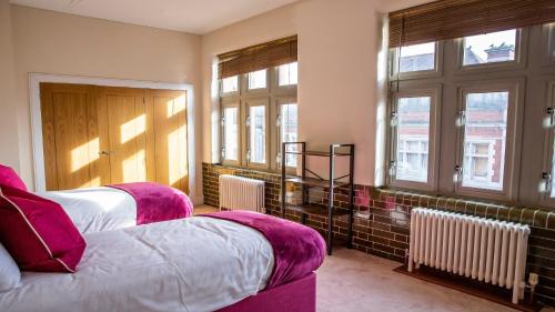 a bedroom with two beds and two windows at Post Office Penthouse in Great Yarmouth