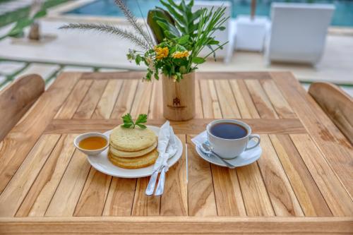 a table with pancakes and two cups of coffee on it at Kelingking Green Village in batumadeg