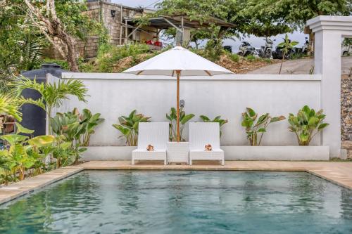 a swimming pool with two chairs and an umbrella next to a house at Kelingking Green Village in batumadeg