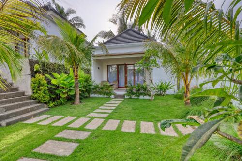 a house with a garden with palm trees at Kelingking Green Village in batumadeg