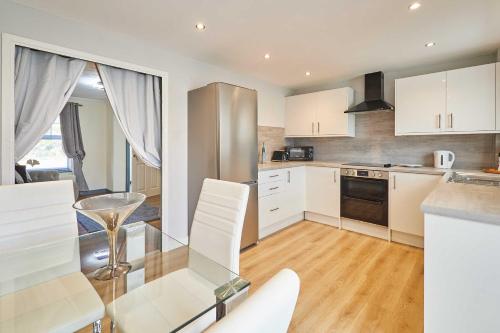 eine Küche mit Glastisch und weißen Schränken in der Unterkunft Host & Stay - Venture Park Villas in Kettering