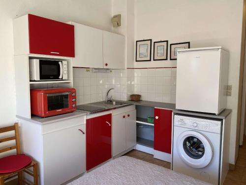 - une cuisine avec des placards rouges et un lave-linge dans l'établissement Studio Confort 2* avec 2 Parkings Privés, Proche Thermes, Calme et Bien Équipé - Balaruc-les-Bains - FR-1-553-114, à Balaruc-les-Bains