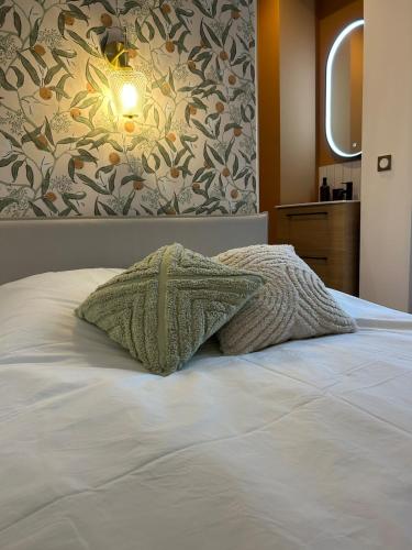 - un lit avec 2 oreillers au-dessus dans l'établissement Le Darcy - Entre Gare et Ville, à Dijon