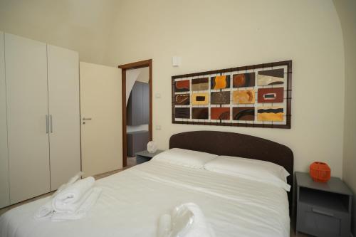 a bedroom with a white bed and a painting on the wall at Al Vico Affittacamere in Matera