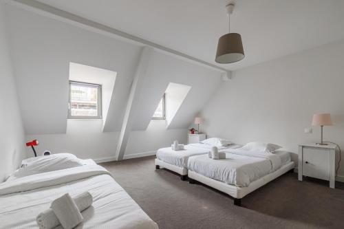 deux lits dans une chambre aux murs blancs dans l'établissement Le Nid de la Krutenau - Joli Duplex à la Krutenau, à Strasbourg