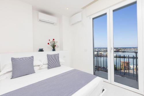 a white bedroom with a bed and a large window at Estate4home - Mary B in Piano di Sorrento