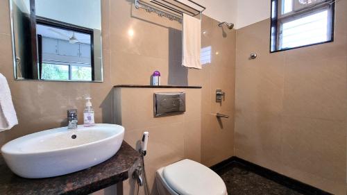 a bathroom with a white sink and a toilet at Villa Vera - 2BHK Apartment in Baga