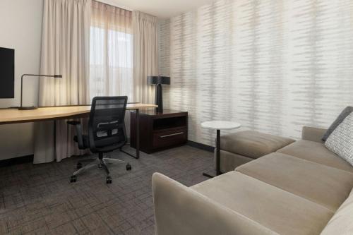 a living room with a couch and a desk with a computer at Residence Inn by Marriott Denver Central Park in Denver